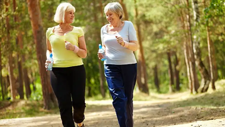Portrait of two senior females running outdoors