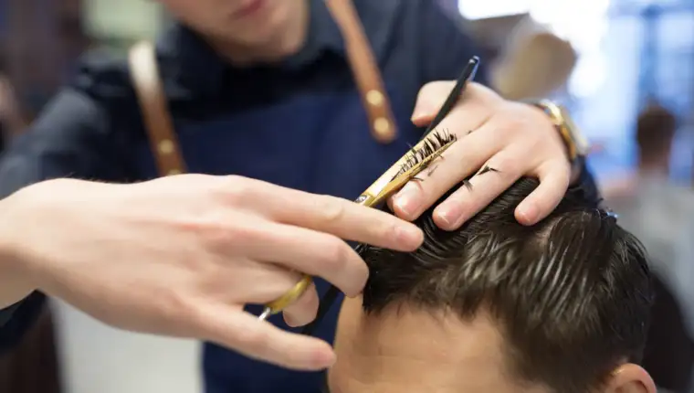 male hairdresser cutting hair at barbershop