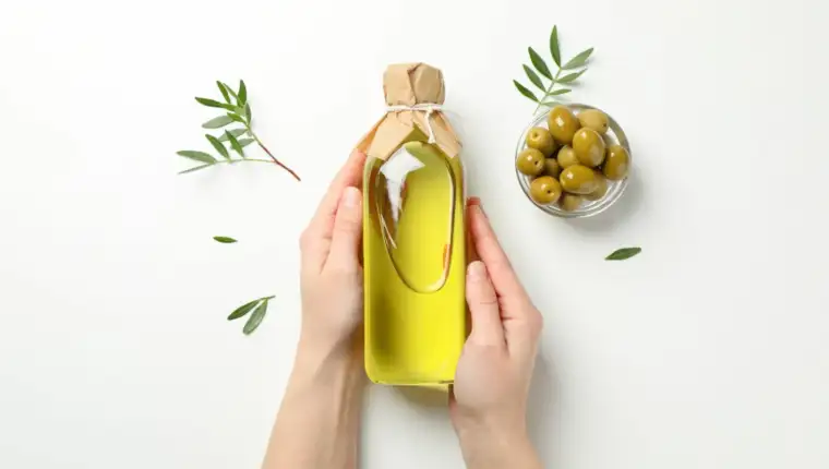 Female hands hold bottle with olive oil on white background, top view