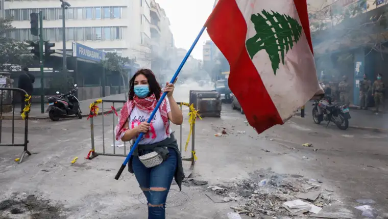 FILE PHOTO: A demonstrator carries a national flag during a protest in Beirut