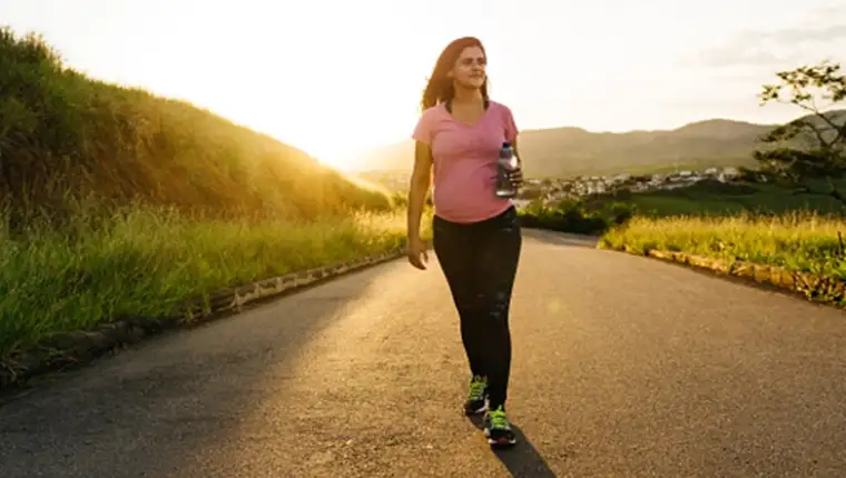 Pregnant woman walking at sunset on a desert road