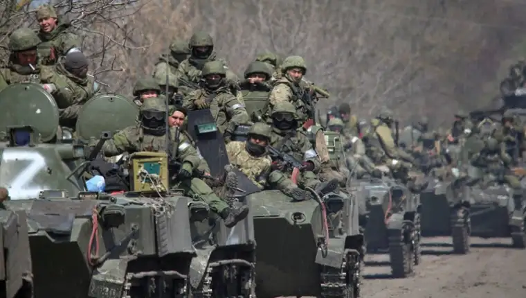 Service members of pro-Russian troops ride on armoured vehicles on a road leading to Mariupol
