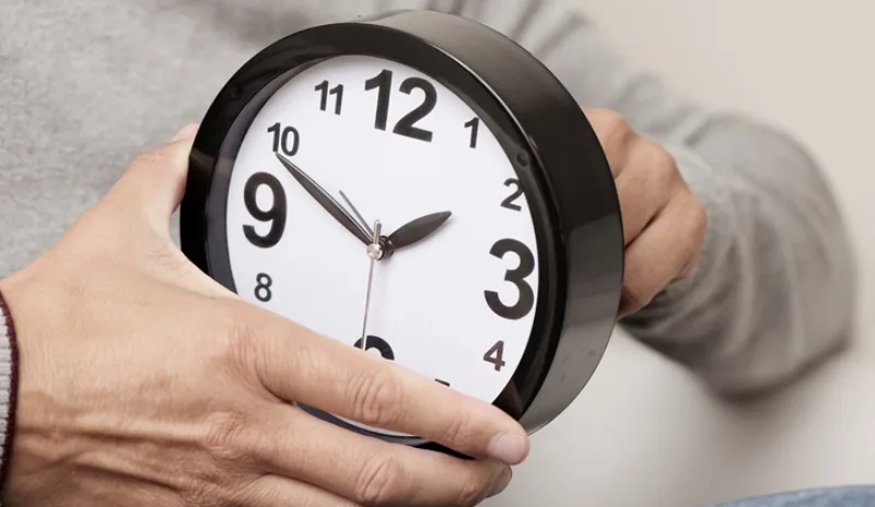 man adjusting the time of a clock