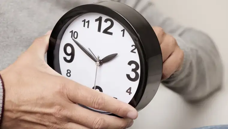 man adjusting the time of a clock