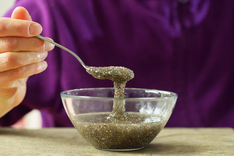 Woman hand with spoon of chia seeds in water