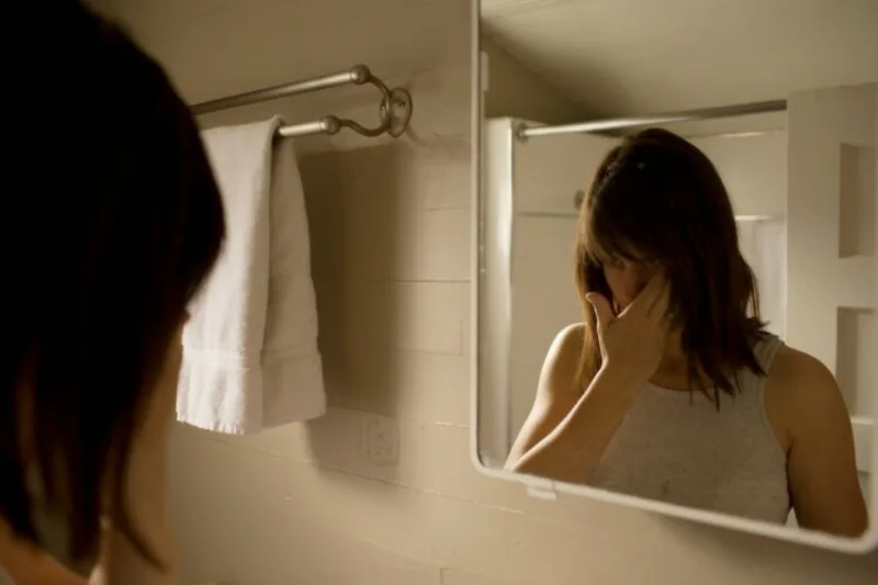 Woman looking in bathroom mirror