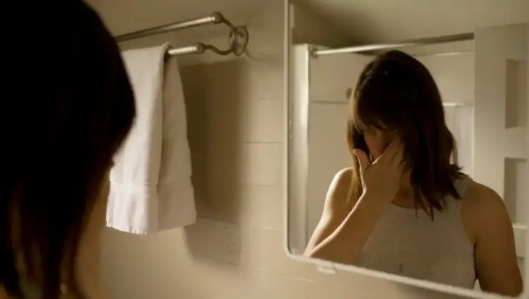 Woman looking in bathroom mirror