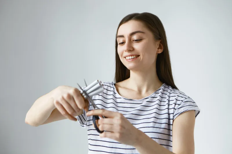 RAPORT_happy-young-european-woman-feeling-free-destructive-unhealthy-tobacco-addiction-holding-several-cigarette-cutting-them-halves-using-scissors