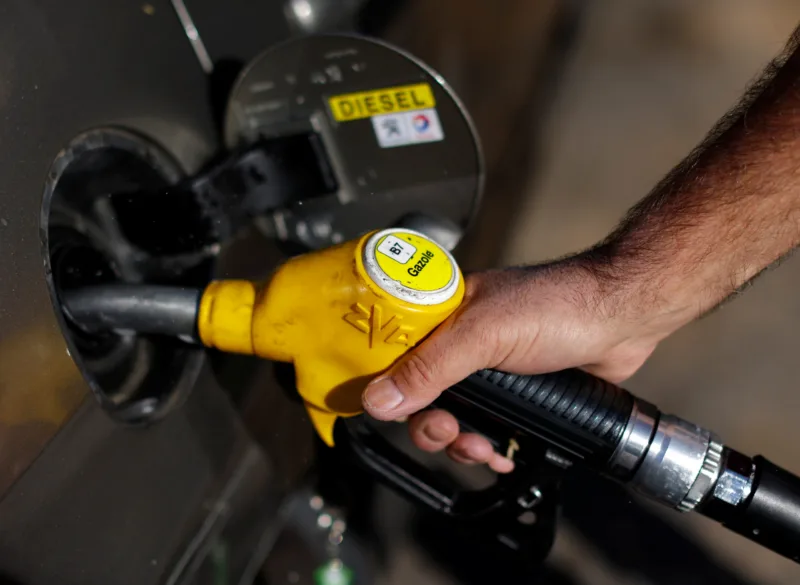 An employee holds a diesel fuel nozzle at a petrol station in Nice