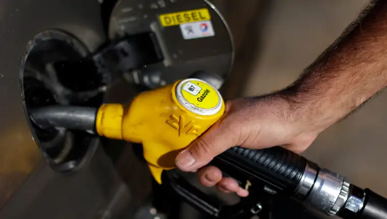 An employee holds a diesel fuel nozzle at a petrol station in Nice