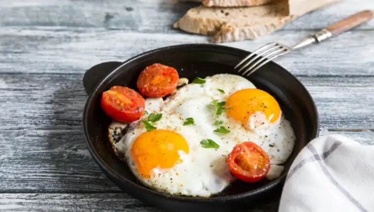 Fried egg. Close up view of the fried egg on a frying pan with cherry tomatoes and parsley