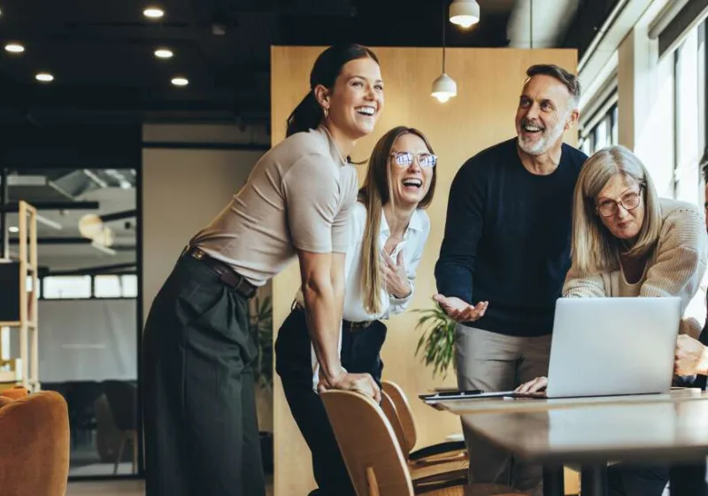 Happy,Businesspeople,Laughing,While,Collaborating,On,A,New,Project,In
