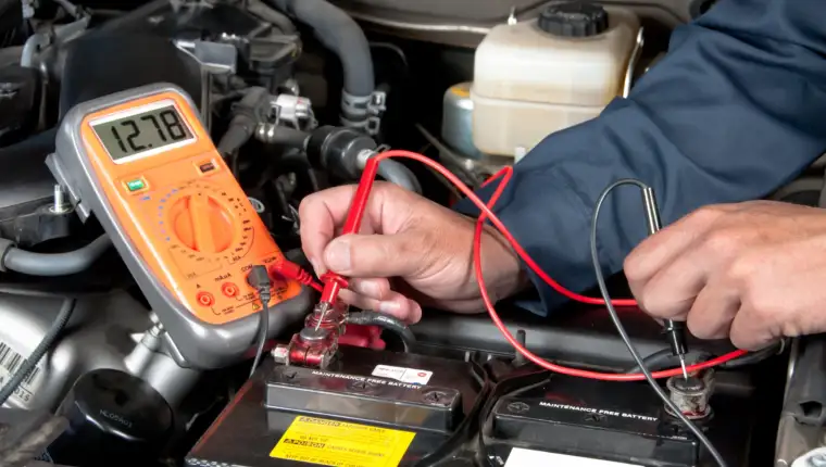 Auto mechanic checking car battery voltage