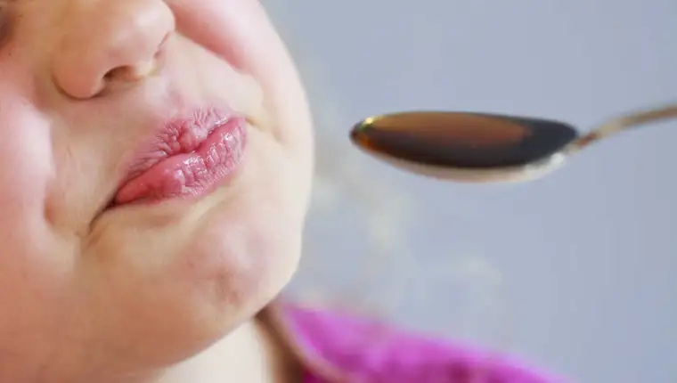 Bitter medicine and girl grimaces