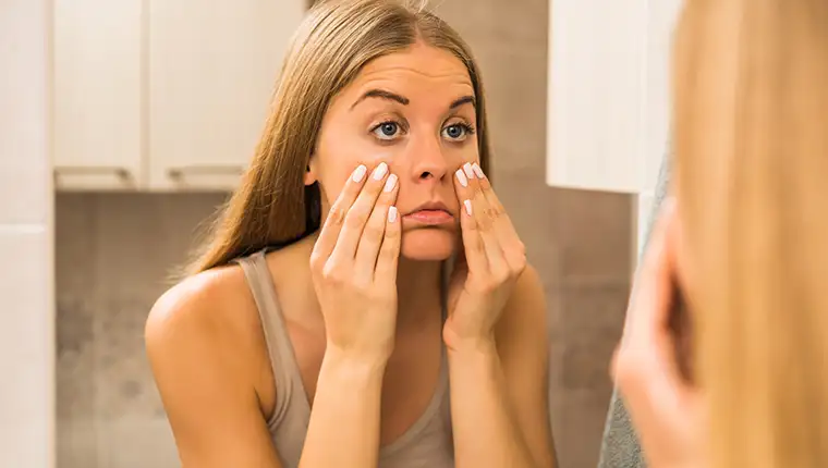 Tired,Woman,Looking,Her,Eye,Bags,In,The,Bathroom.