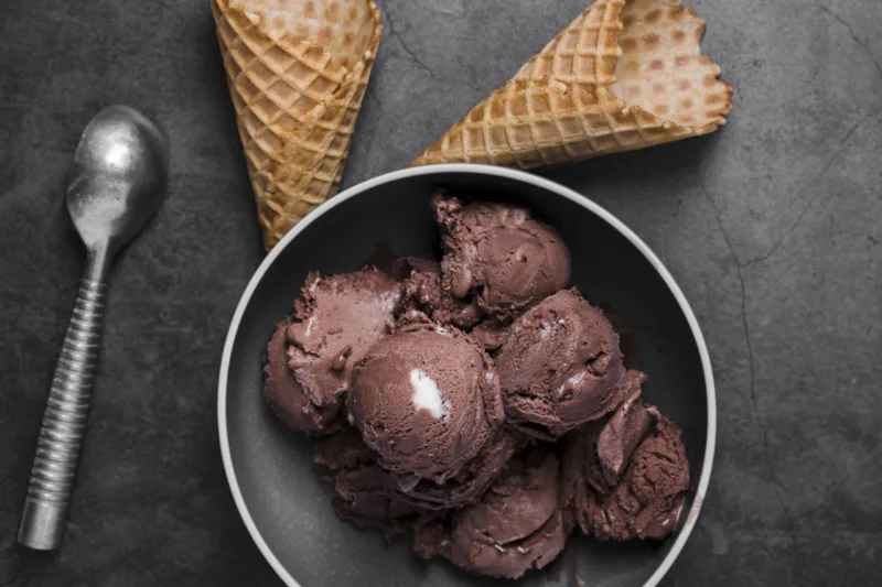top-view-plate-with-chocolate-ice-cream-scoops-cones-beside