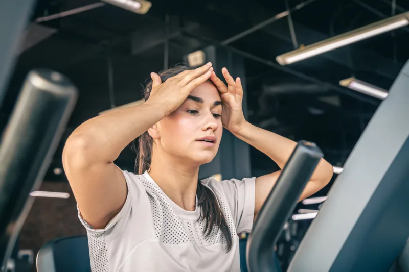 A young woman tired after intense workout on the exercise bike at the gym.