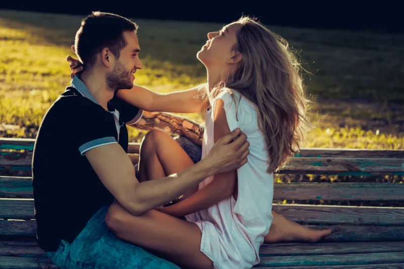 a man and a woman are sitting on a bench and kissing. boyfriend