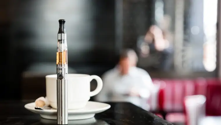 E-cigarette on a bar counter with a cup of coffee