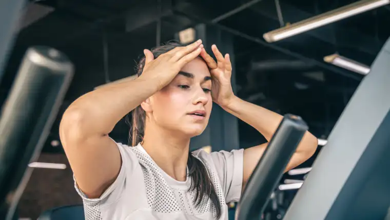 A young woman tired after intense workout on the exercise bike at the gym.