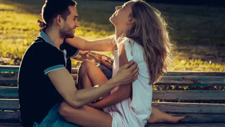 a man and a woman are sitting on a bench and kissing. boyfriend