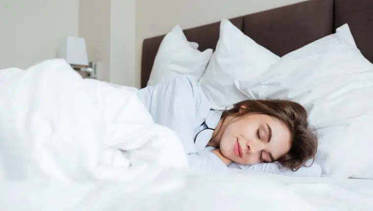 Cheerful young lady dressed in pajama sleeping in bed