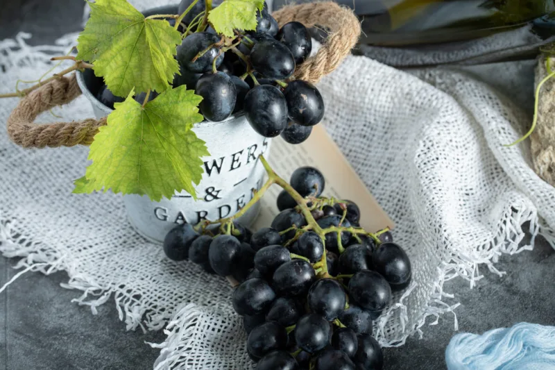 Fresh grapes with leaves in bucket on sackcloth