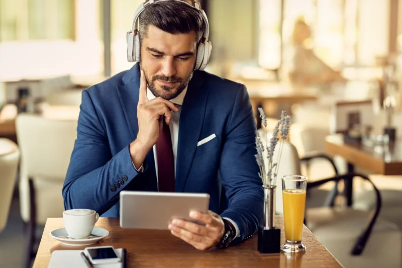 Businessman wearing headphones while surfing the net on touchpad
