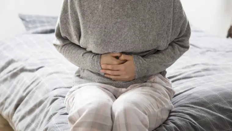 Sick woman with hands on stomach suffering from intense pain