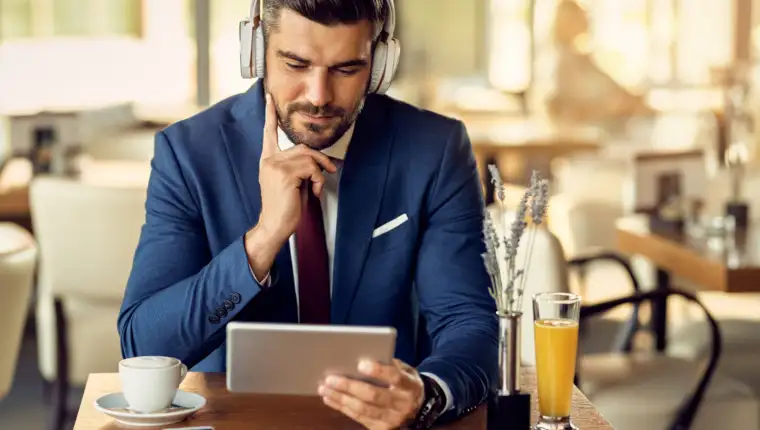 Businessman wearing headphones while surfing the net on touchpad