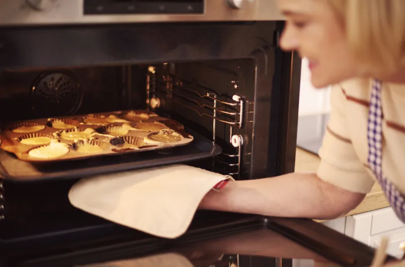 Woman pulls muffins from the oven