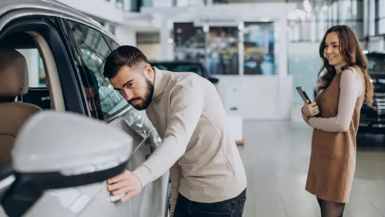 Handsome man choosing a car in a car showroom