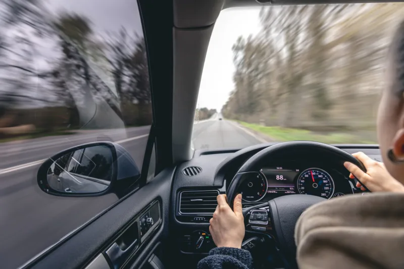 Woman driver's hands on a car steering wheel.