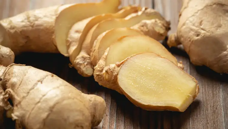 Fresh ginger root and sliced on wooden table.