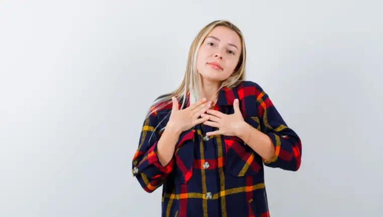young lady holding hands on chest in checked shirt and looking hopeful. front view.