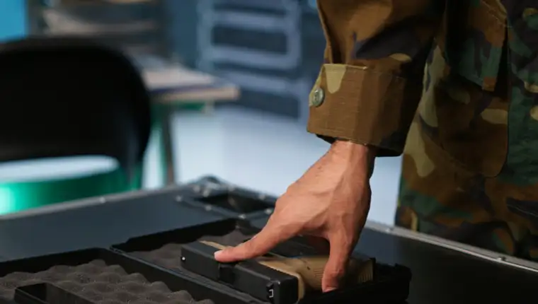 Close up of soldier holding pistol, managing combat load equipment