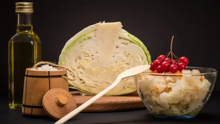 Fermented cabbage with herbs and spices in glass bowl on the black background