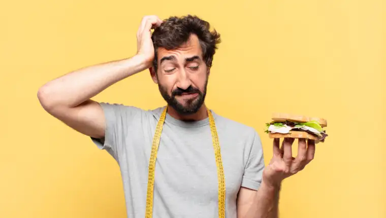 young crazy bearded man dieting sad expression and holding a sandwich