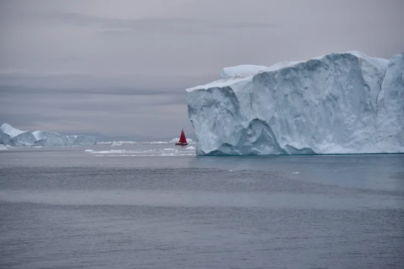 scenic-view-red-sails-against-huge-icebergs
