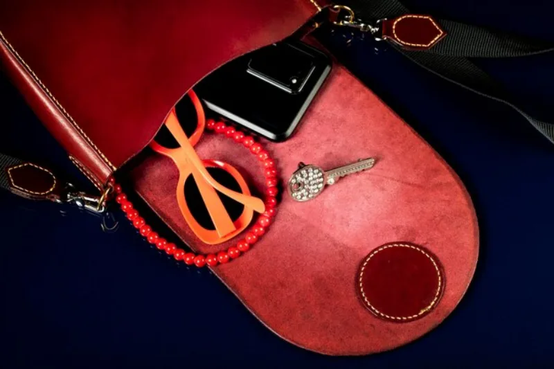 red-leather-bag-with-women-s-accessories-dark-background_186673-8725