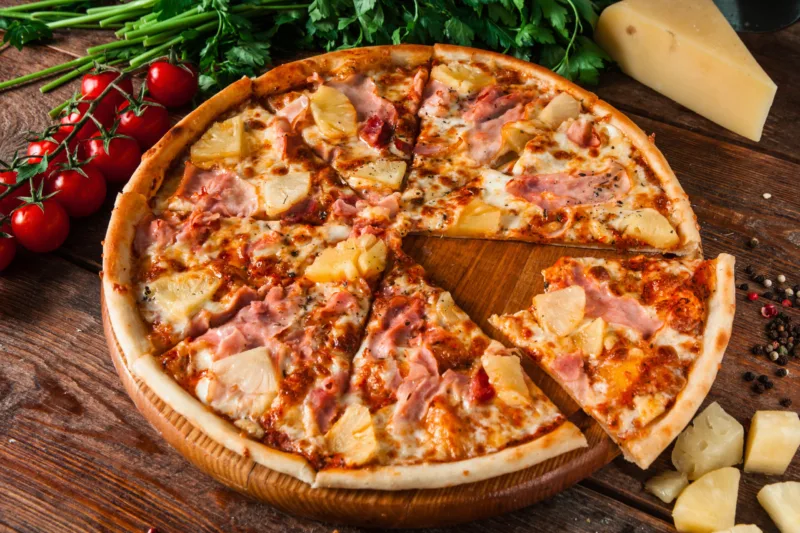 Hawaiian pizza with cut out bitten slice, top view