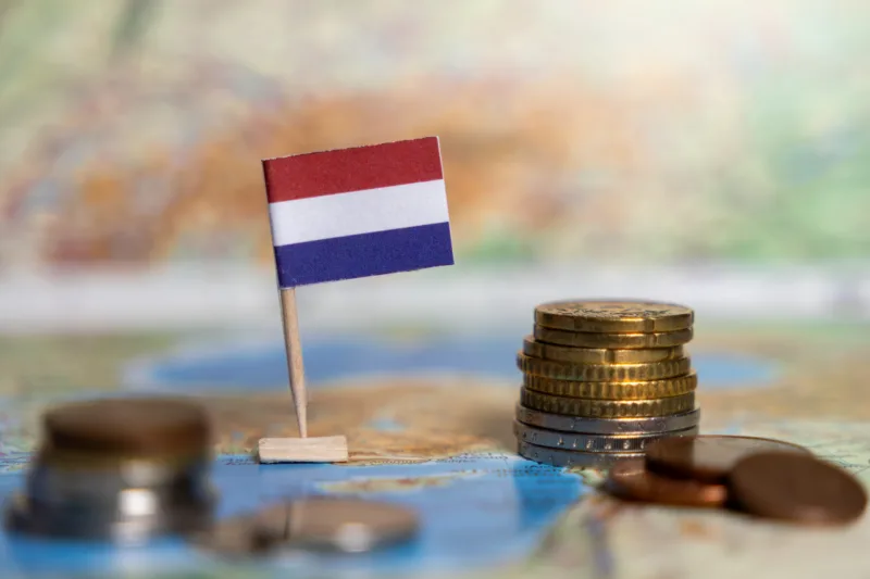 dutch flag with euro coins on a world map, symbolizing the netherlands economy, financial stability, and international trade connections