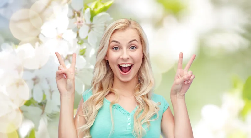 smiling young woman or teenage girl showing peace
