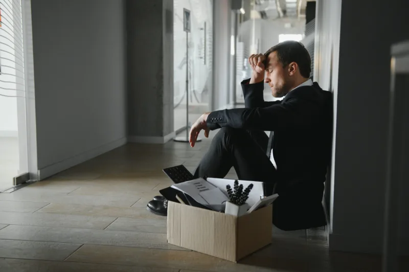 Sad Fired. Let Go Office Worker Packs His Belongings into Cardboard Box and Leaves Office. Workforce Reduction, Downsizing, Reorganization, Restructuring, Outsourcing. Mass Unemployment Market Crisis