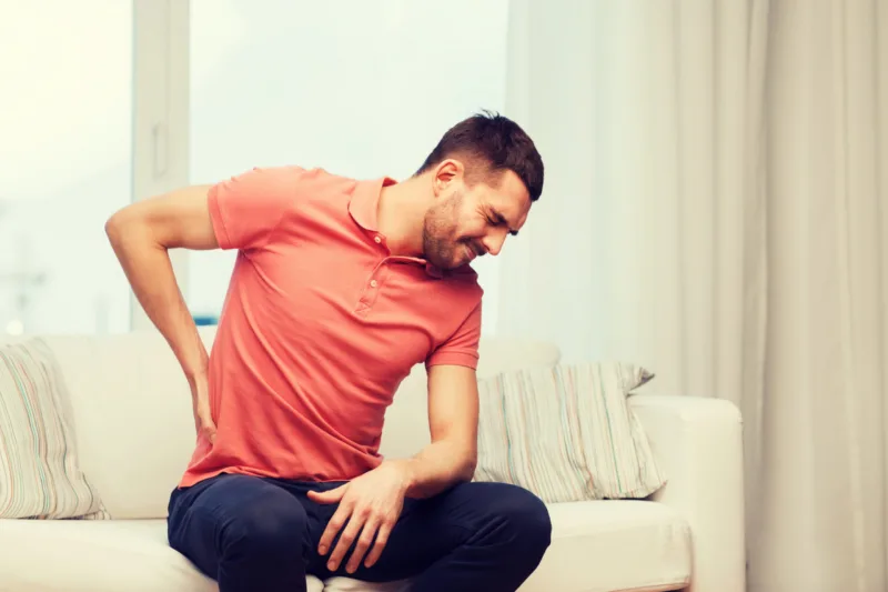 unhappy man suffering from backache at home