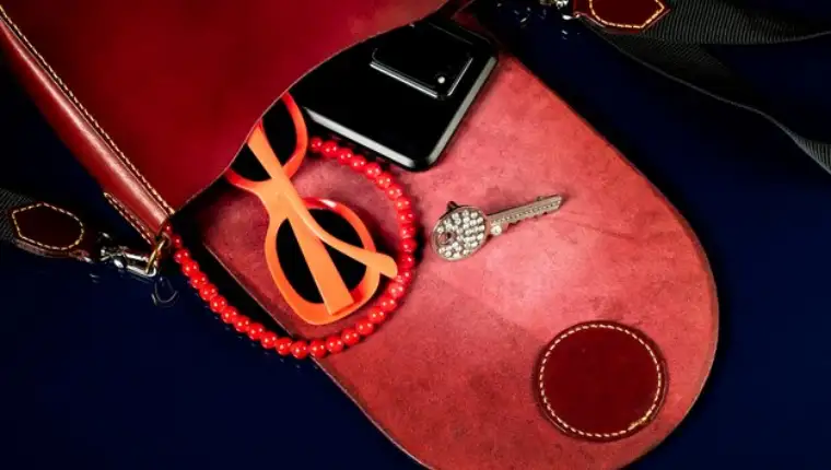 red-leather-bag-with-women-s-accessories-dark-background_186673-8725