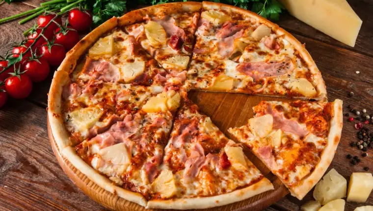 Hawaiian pizza with cut out bitten slice, top view