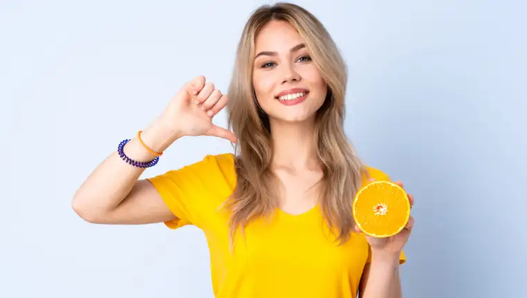 Teenager Russian girl holding an orange isolated on blue background proud and self-satisfied