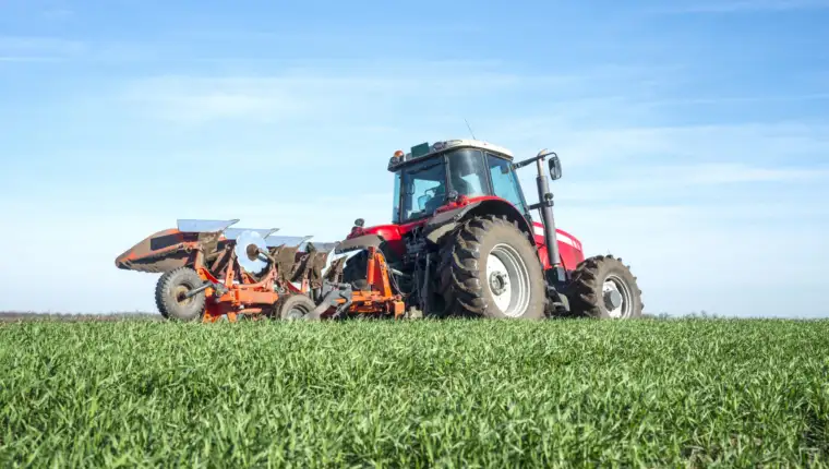 Tractor agricultural machine cultivating field.