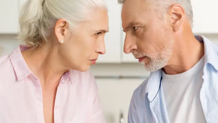 Angry mature man standing near mature serious woman